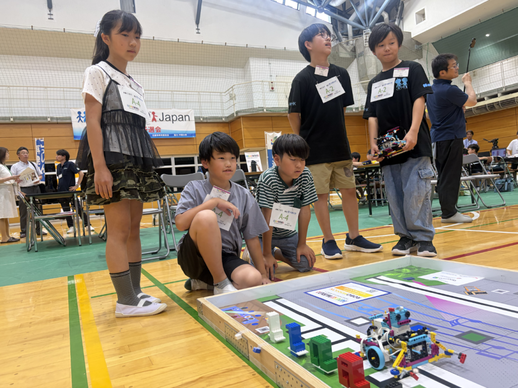 競技コートでロボットの走行を見守るエレメンタリー部門の生徒たち