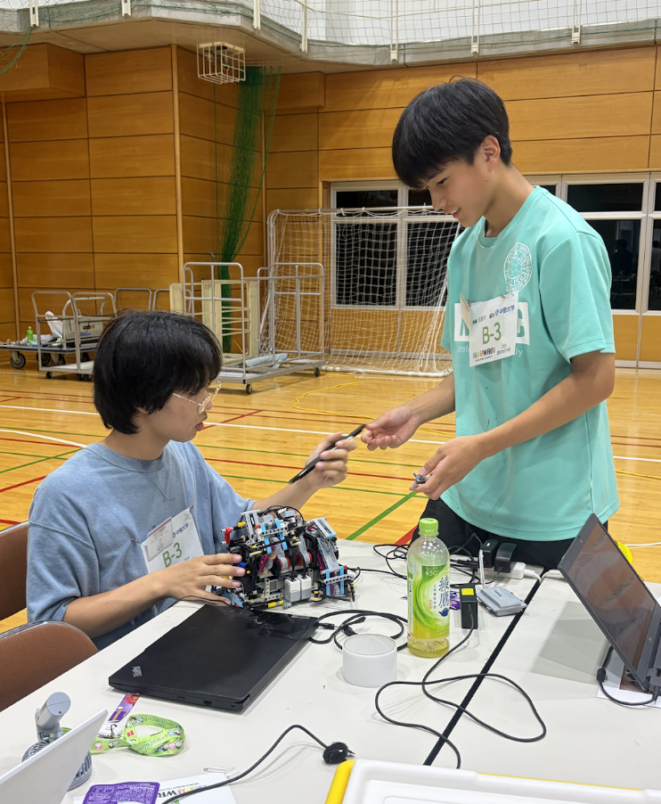 ロボットを調整するジュニア部門の生徒